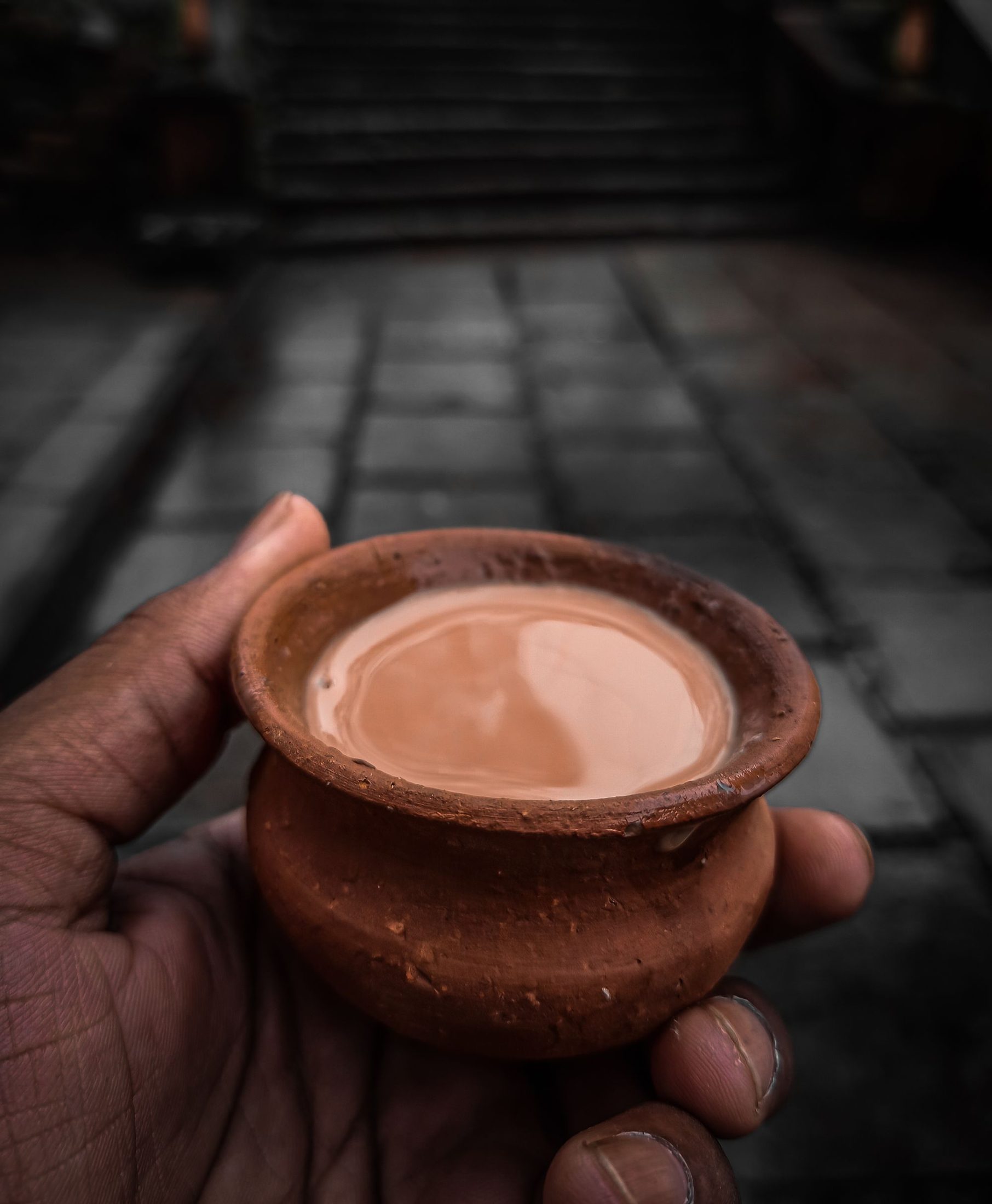 A hand cradling a clay cup of chai on a dark street